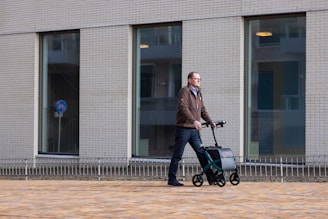 a man pushing a stroller with a suitcase on wheels