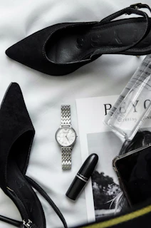a woman's purse with a watch, lipstick, and other items