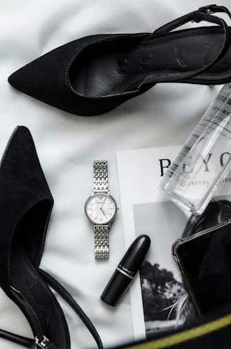 a woman's purse with a watch, lipstick, and other items