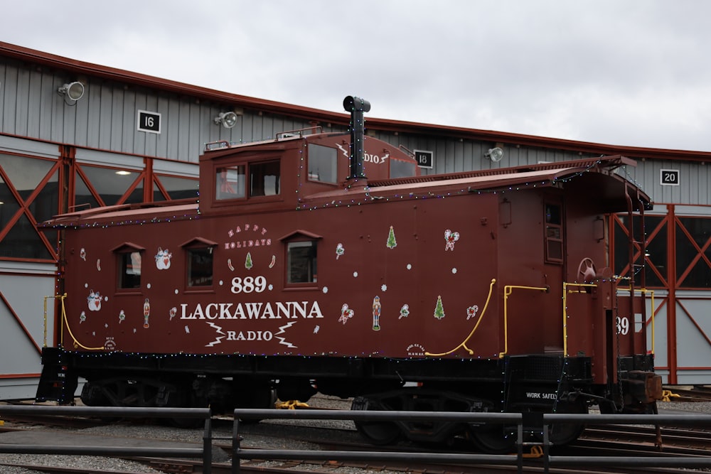 a red train car sitting in front of a building