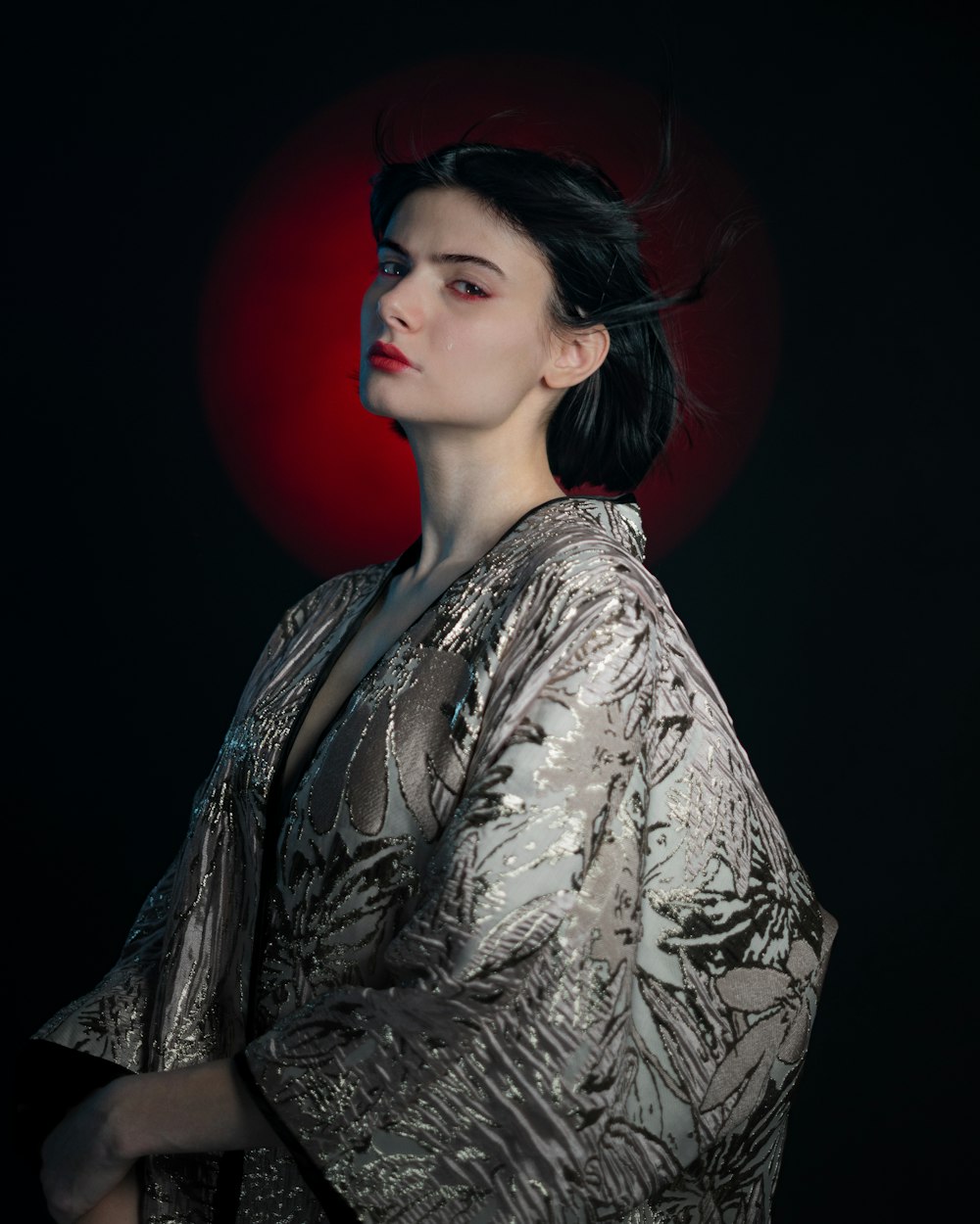 a woman in a kimono standing in front of a red light