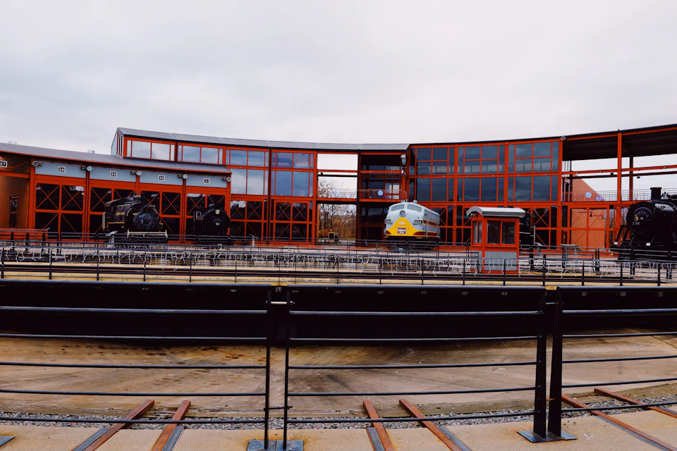 Large, modern building with orange facade and curved roof on a railway track platform