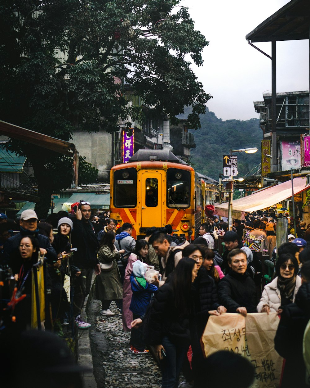 a crowd of people walking down a street next to a train