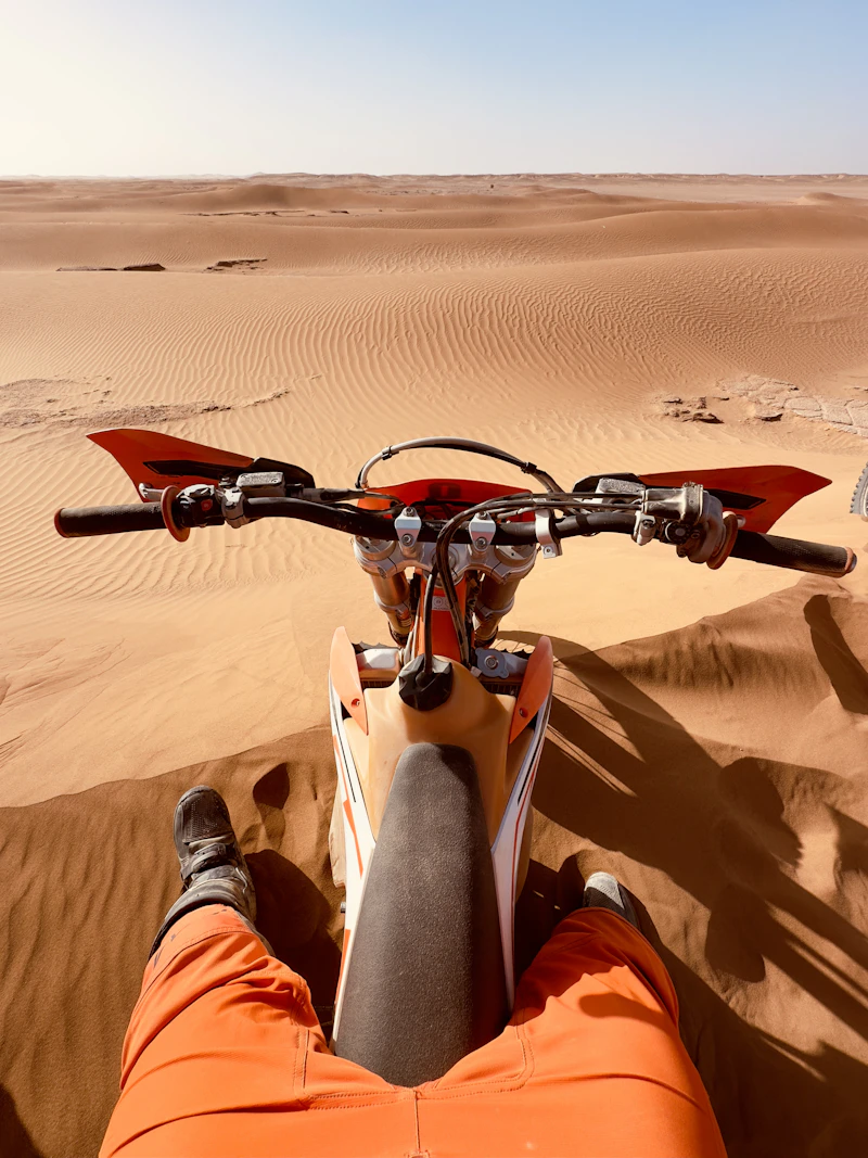 Rider on a motorbike crossing the Sahara at sunset