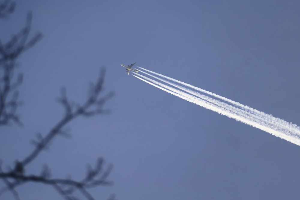 un avión volando en el cielo dejando un rastro de humo detrás de él
