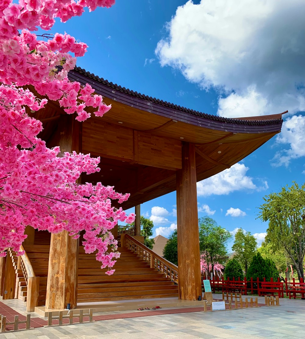 a large wooden structure with pink flowers in front of it