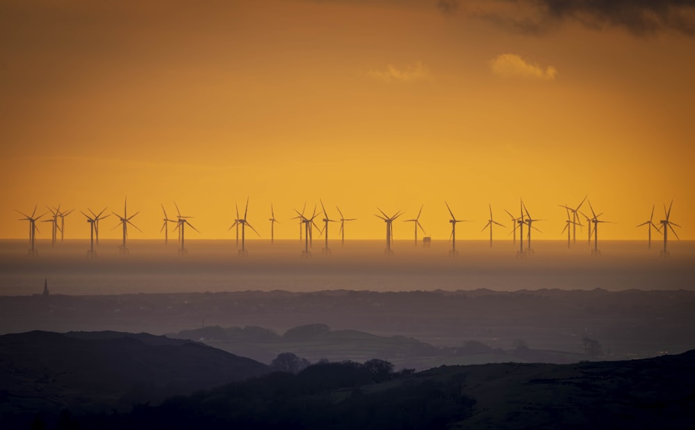 a group of windmills on a hill at sunset