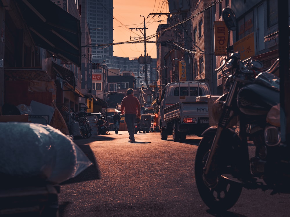 a man walking down a street next to a motorcycle
