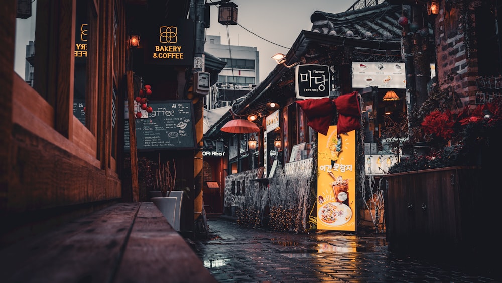 a wet street with signs and umbrellas on a rainy day