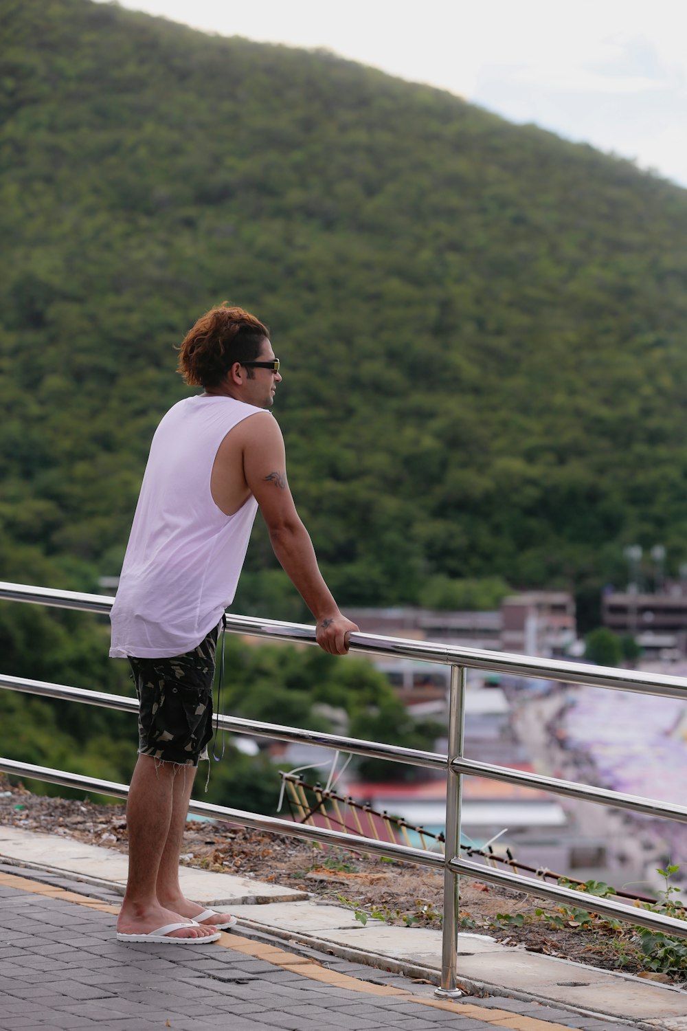 a man standing on top of a metal rail next to a lush green hillside