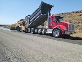 a red dump truck driving down a road