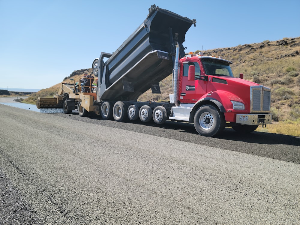 a red dump truck driving down a road