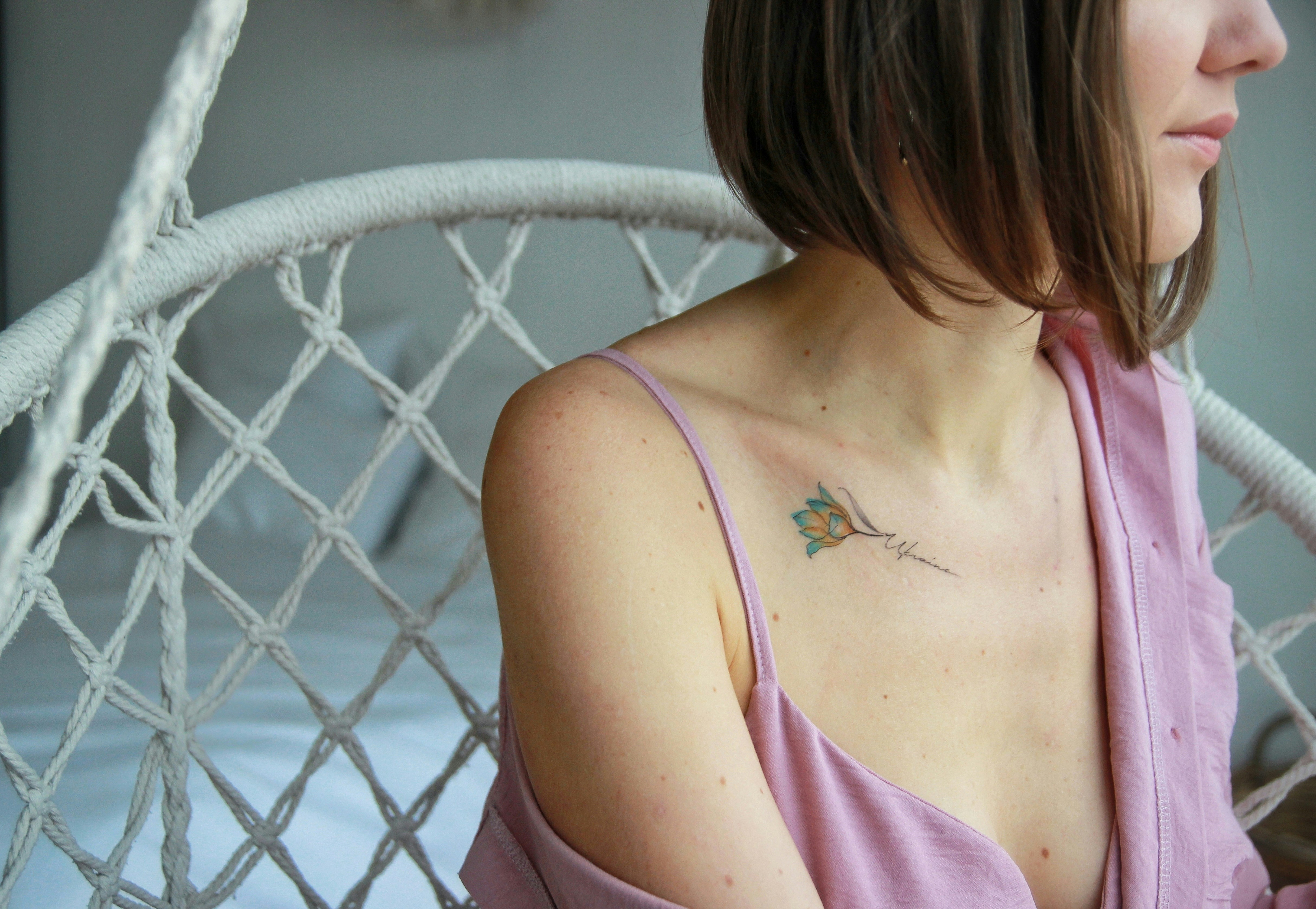a woman sitting in a chair with a tattoo on her chest