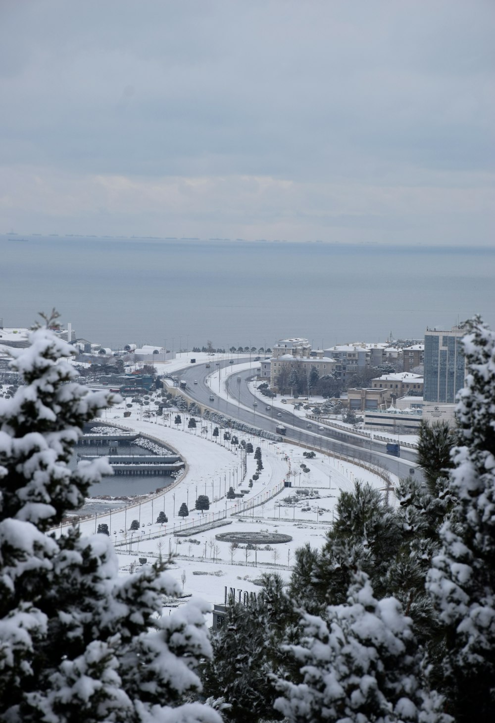 a snowy view of a highway and a body of water