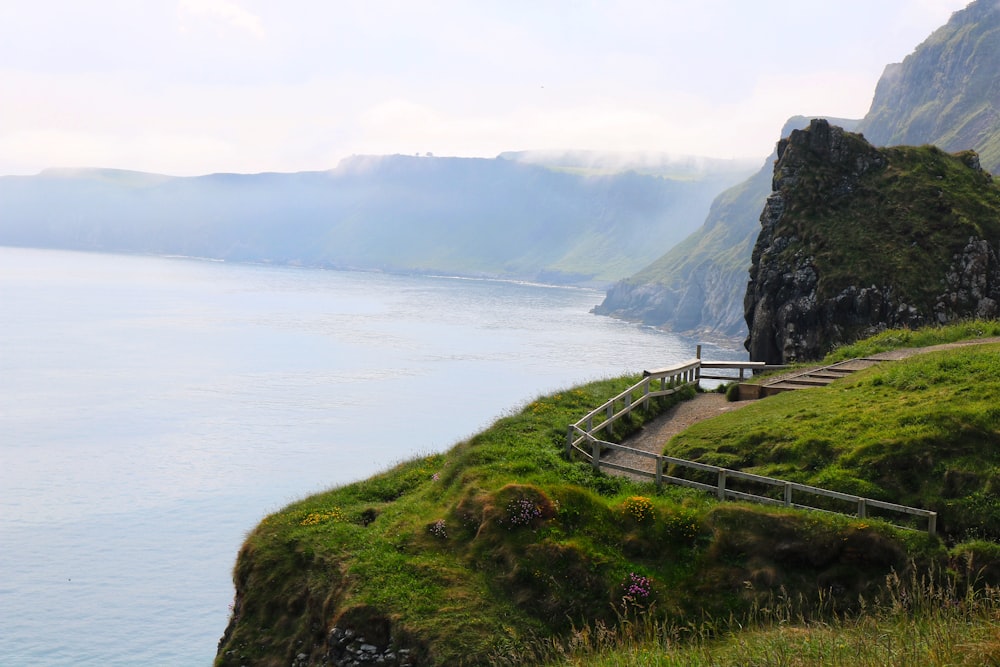 a bench sitting on the side of a cliff overlooking a body of water