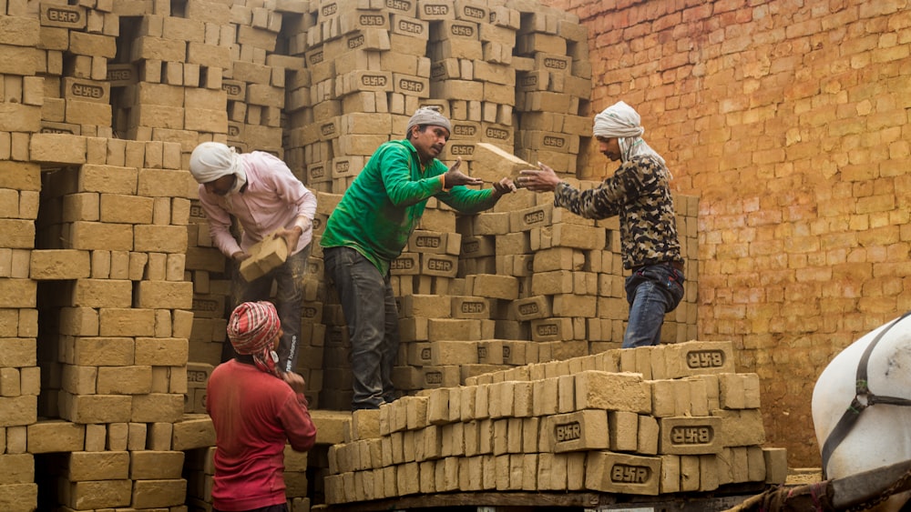 a group of people standing around a pile of bricks