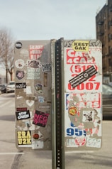a parking meter covered in stickers on a city street