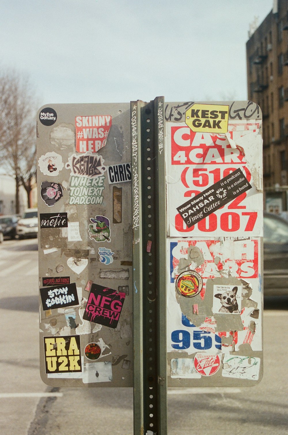 a parking meter covered in stickers on a city street