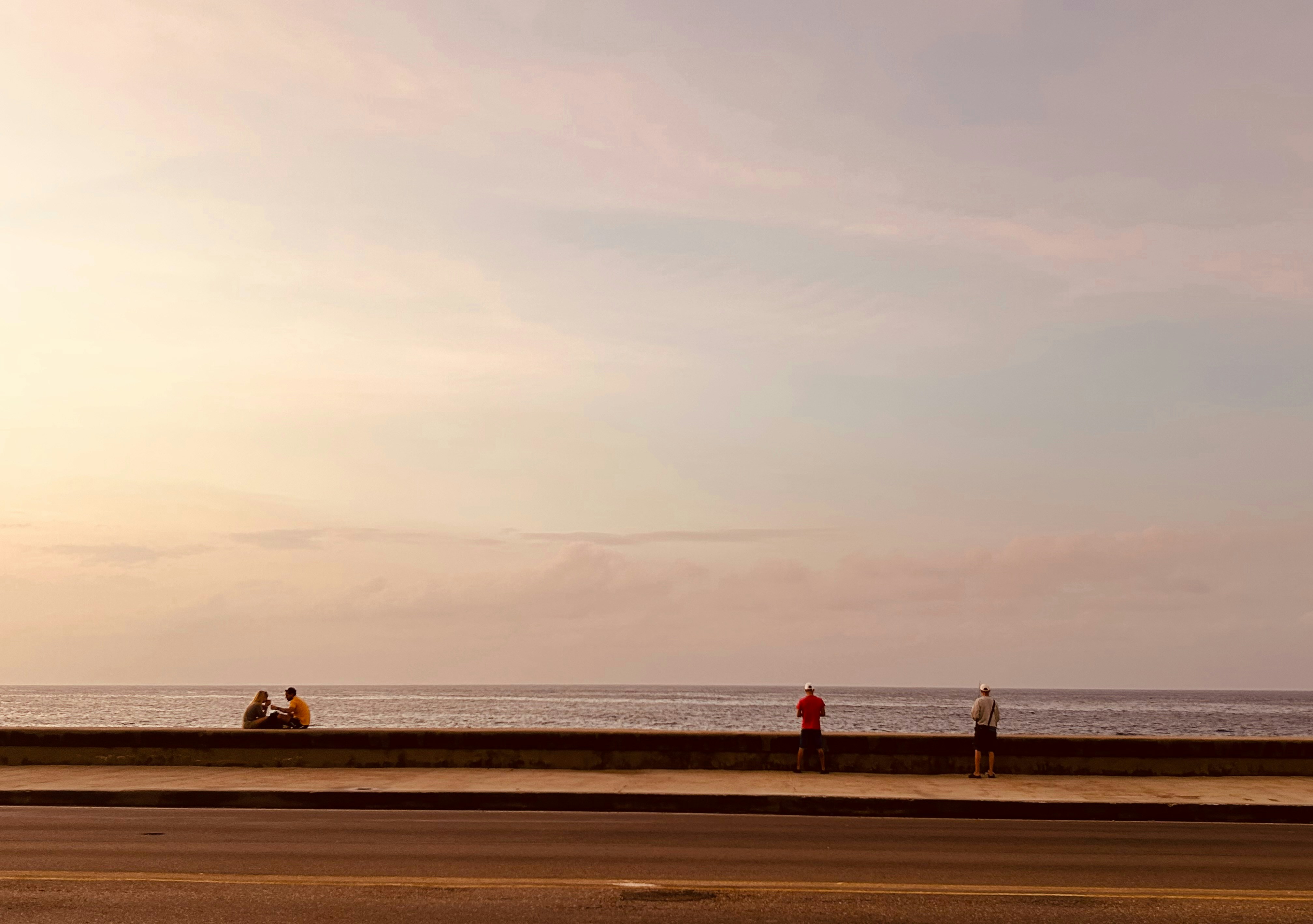 a group of people standing on the side of a road next to the ocean