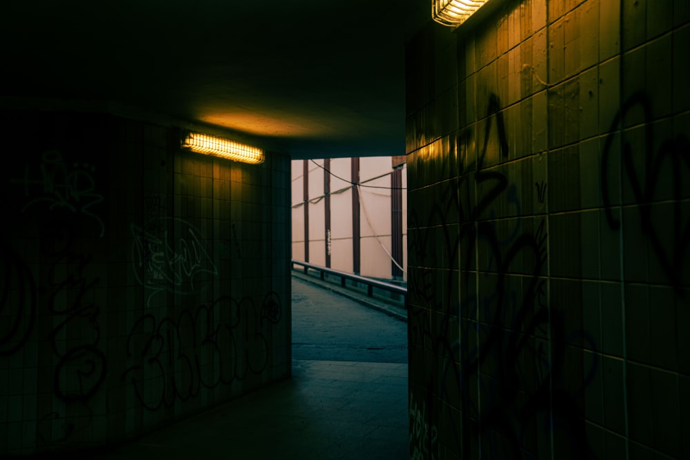 a dimly lit hallway with graffiti on the walls
