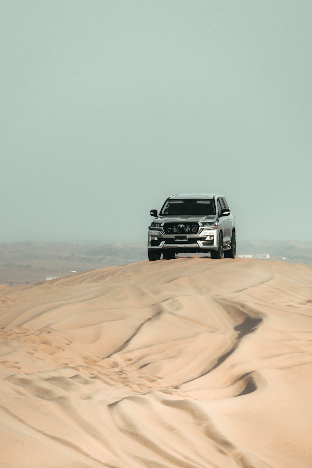 a white truck driving across a sandy field