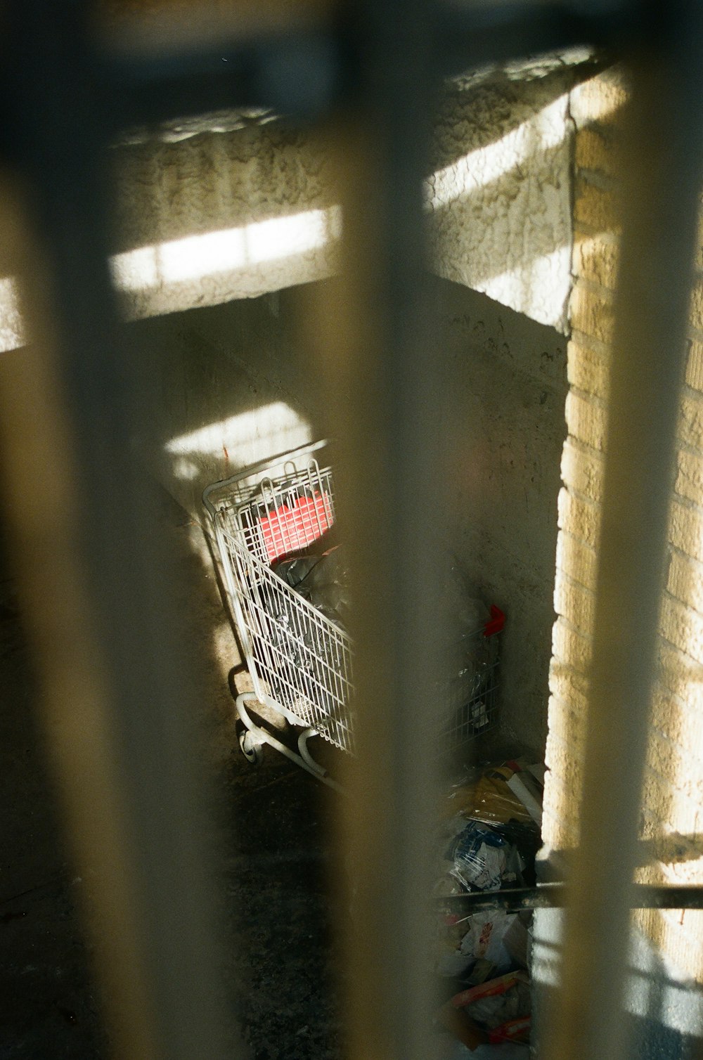 a shopping cart is seen through the bars of a gate