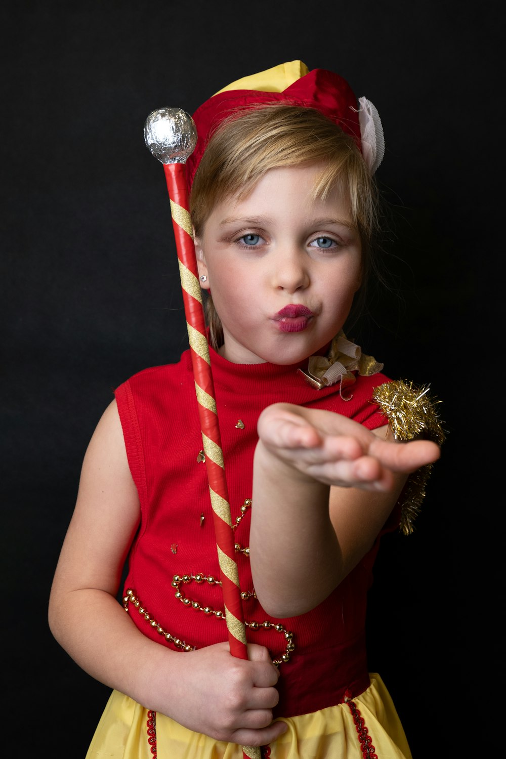 a little girl dressed in a costume holding a candy cane