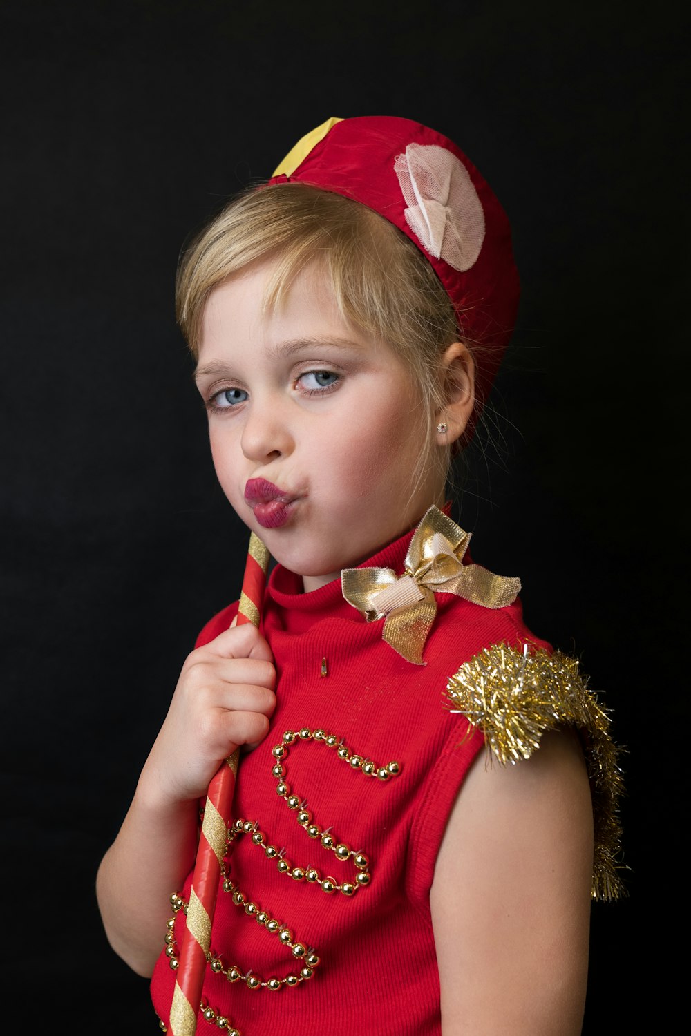 a little girl in a red uniform holding a red stick