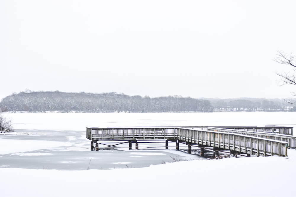 a snow covered field with a wooden bridge