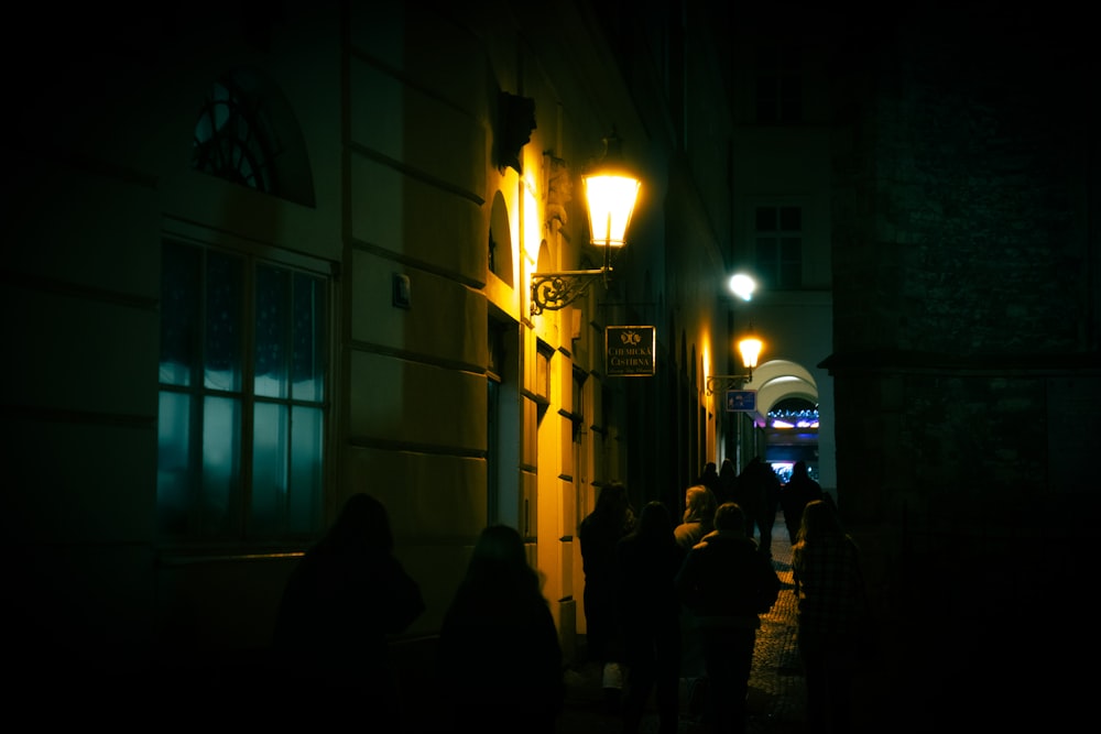 a group of people walking down a street at night