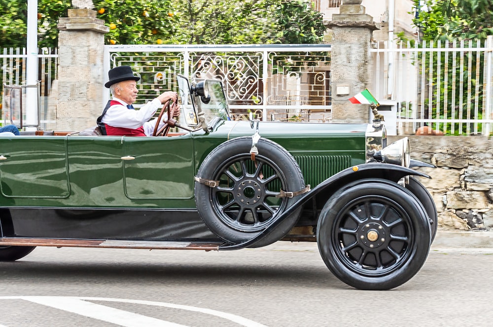 a man driving a green car down a street