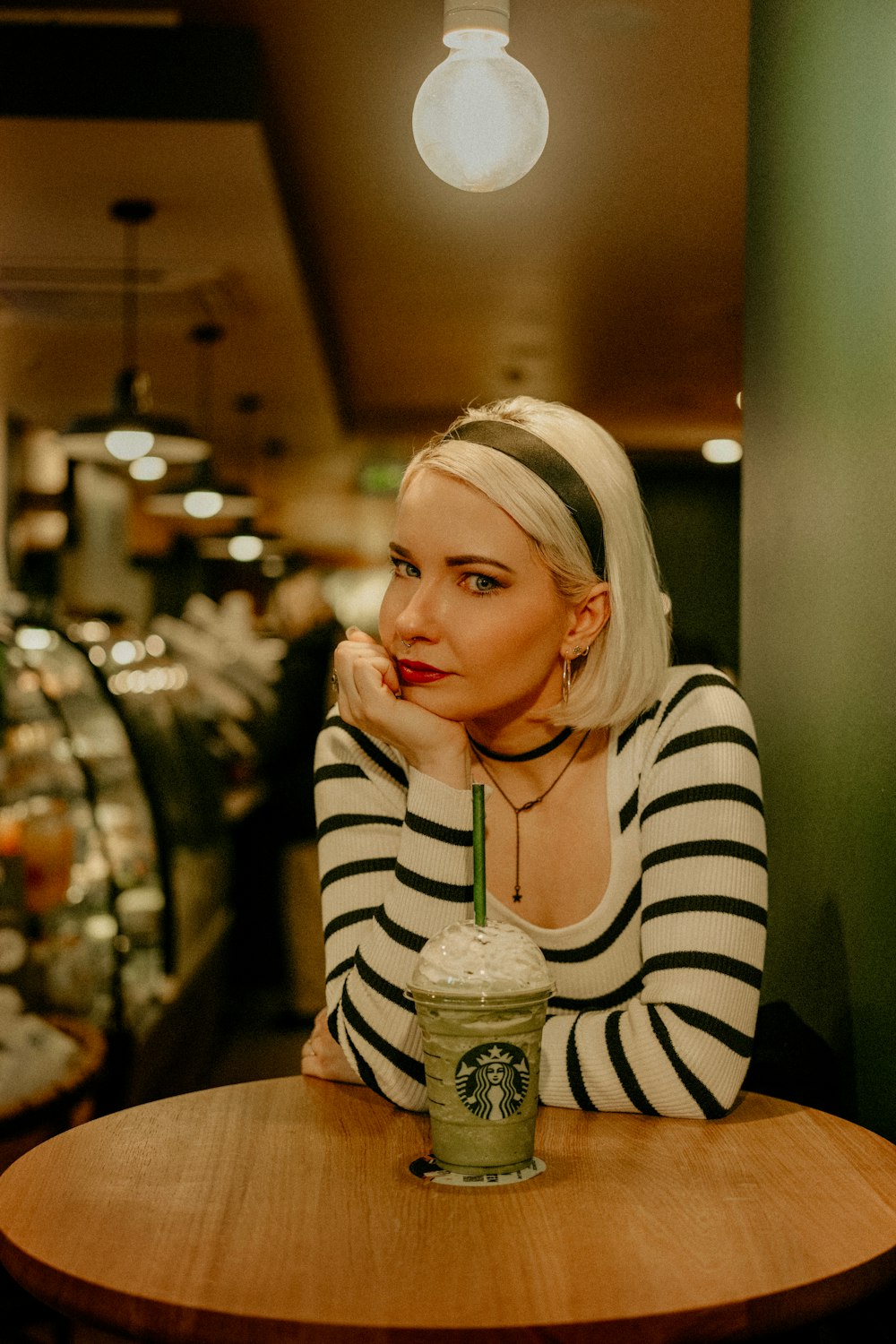 a woman sitting at a table with a starbucks drink
