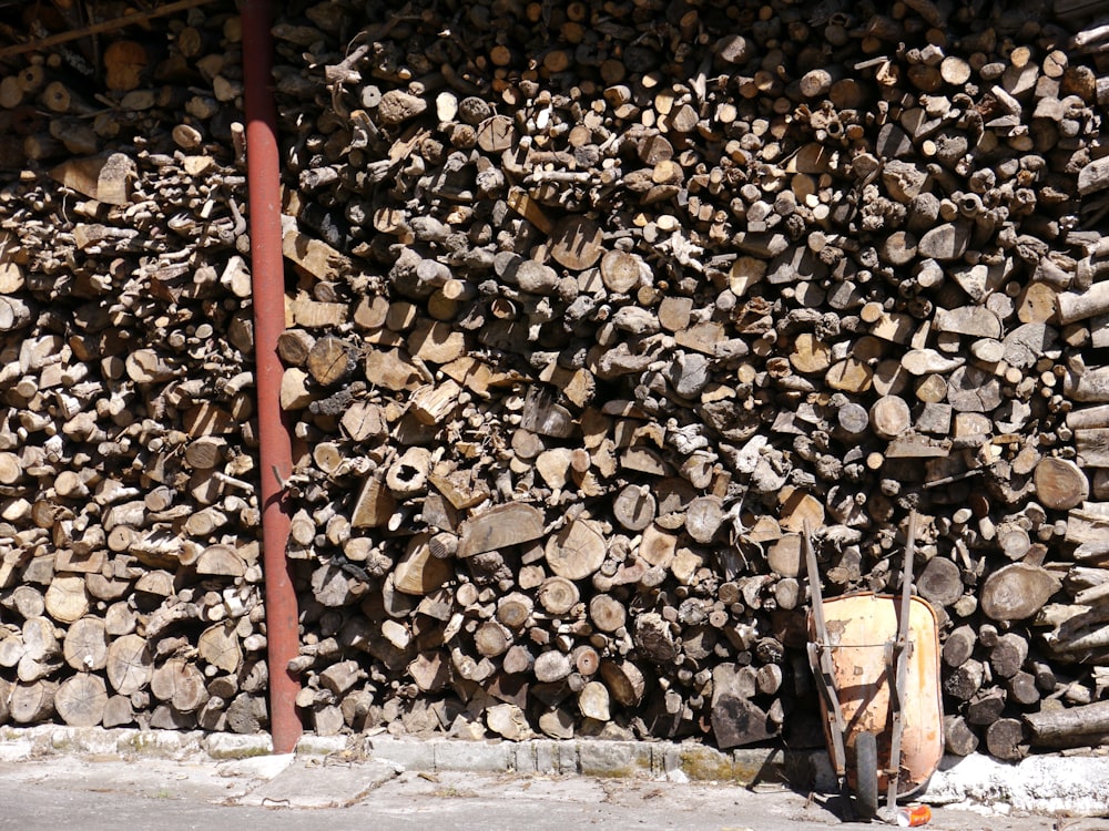 a pile of wood sitting next to a red pole