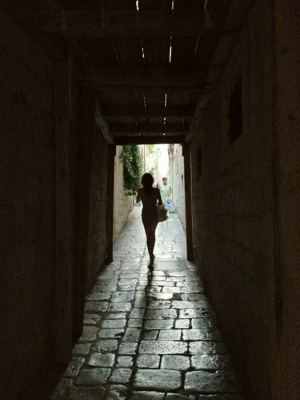 a woman walking down a dark alley way