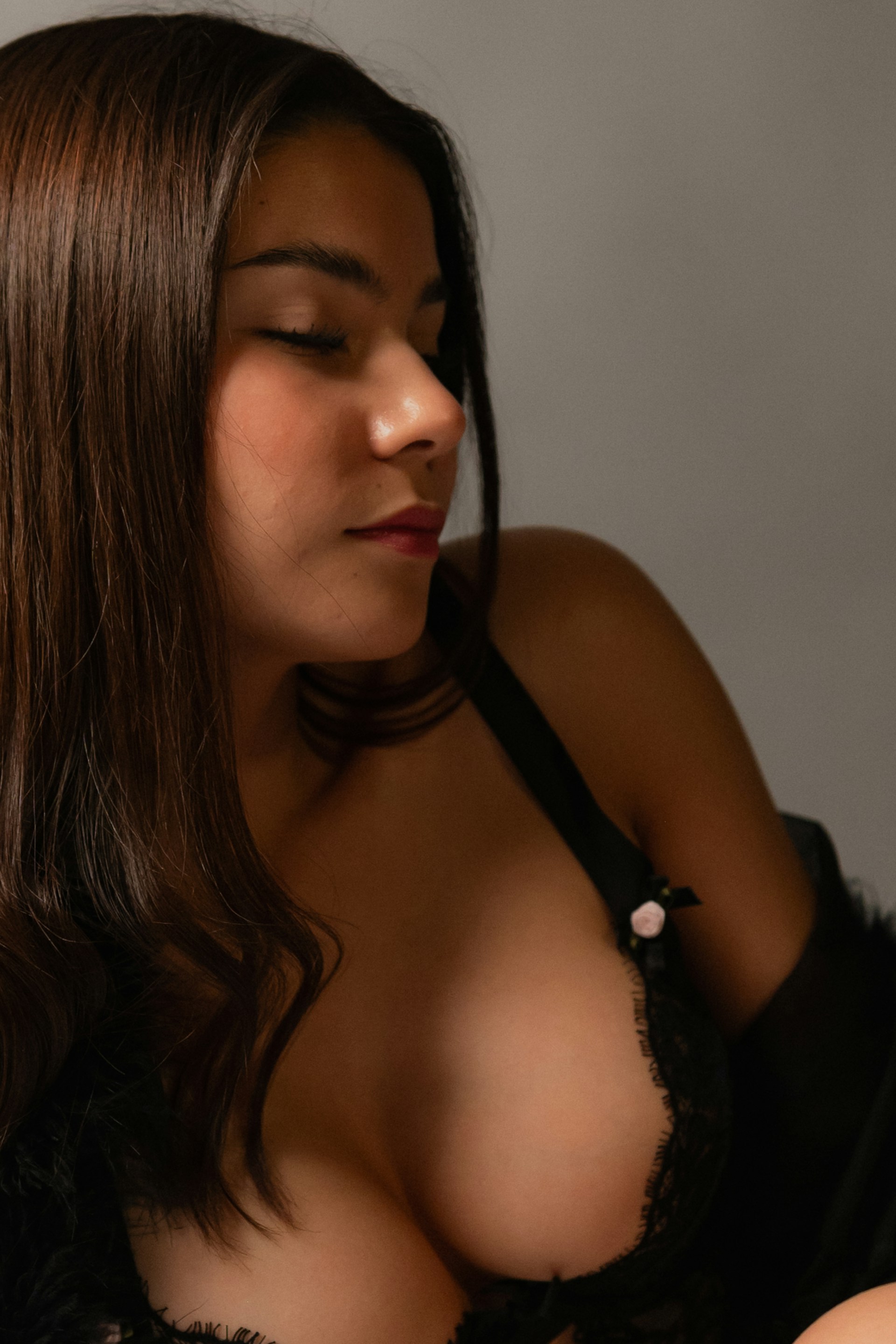 a woman wearing a black bra with her eyes closed