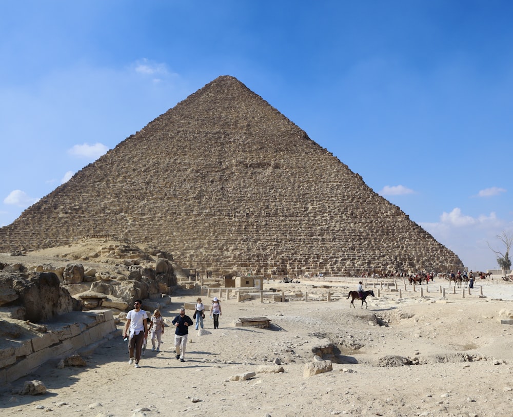 um grupo de pessoas caminhando em frente a uma pirâmide