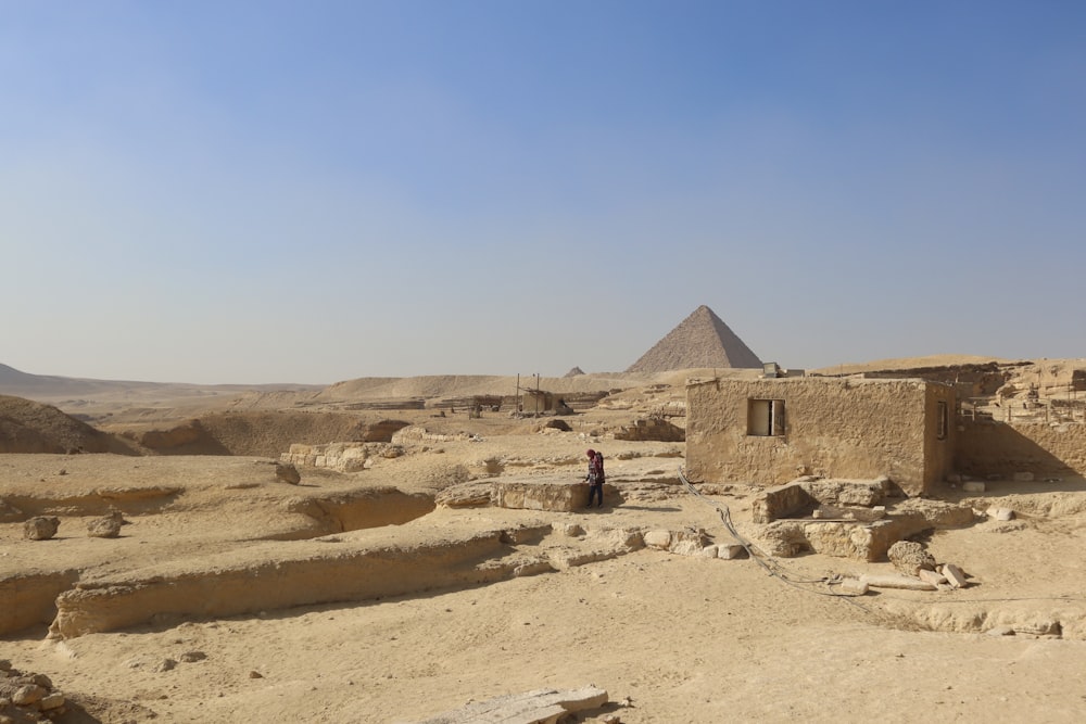 um homem parado em frente a uma pirâmide no deserto