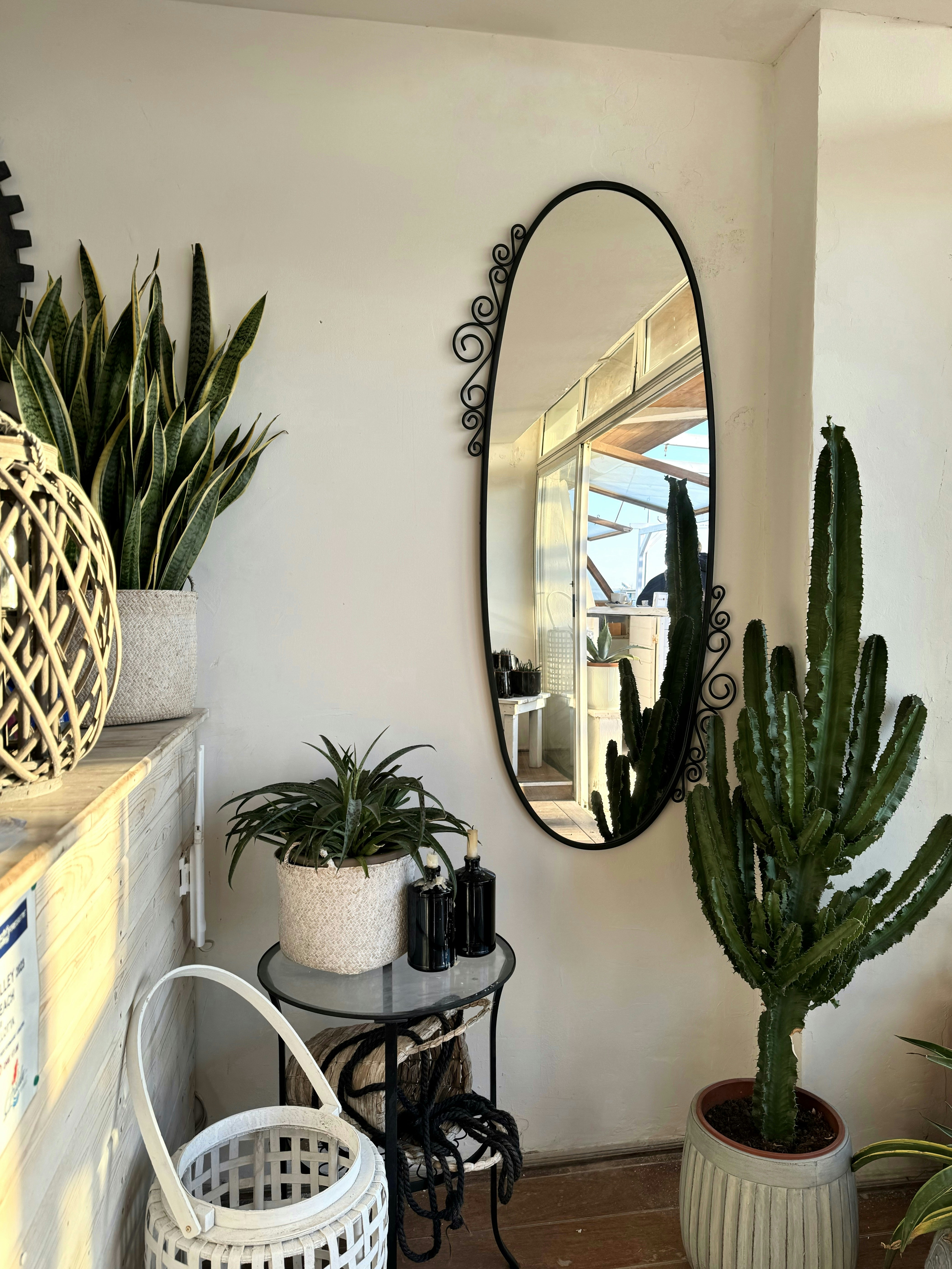 a room with a mirror, potted plants and a table