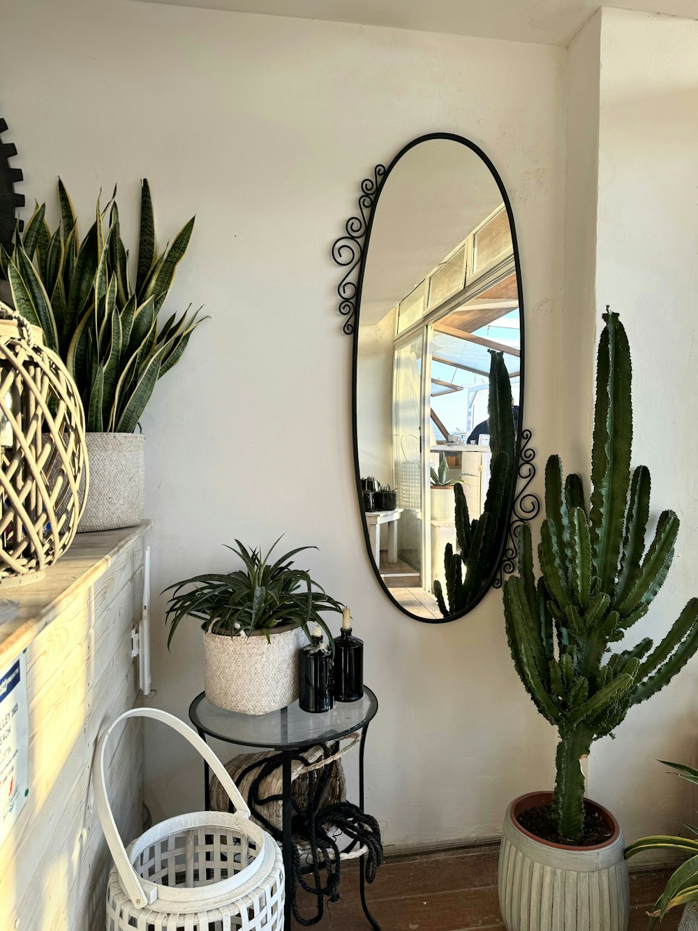 a room with a mirror, potted plants and a table
