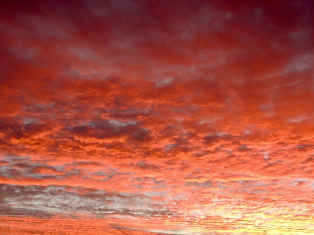 a red and yellow sky with clouds at sunset