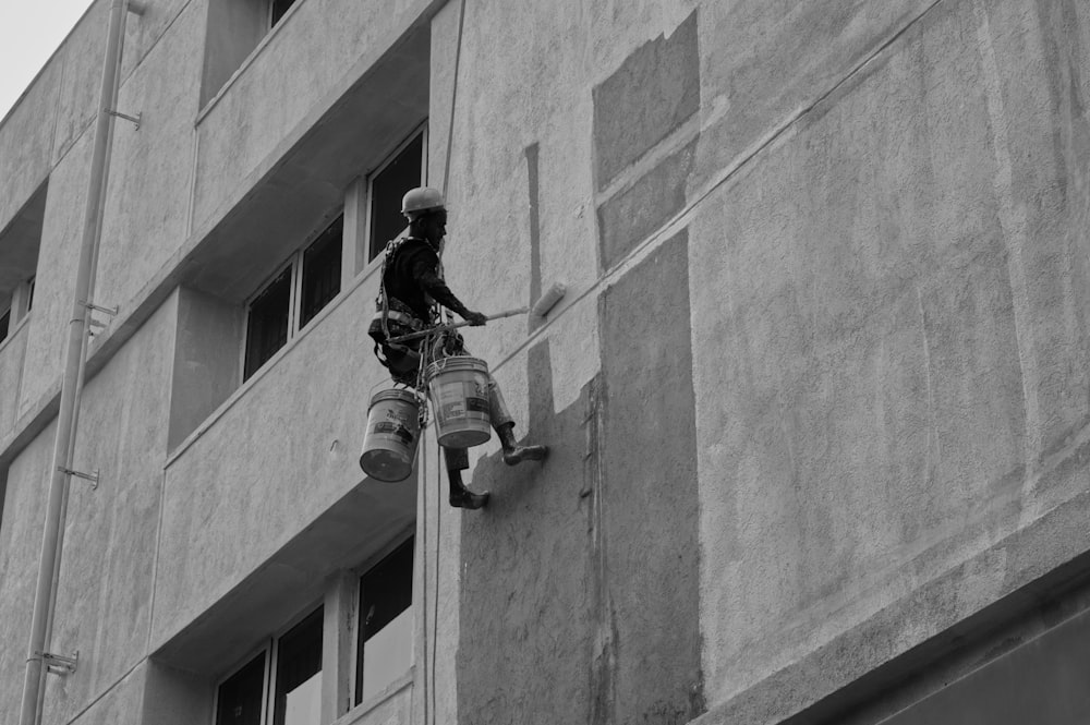 a black and white photo of a man on a ladder