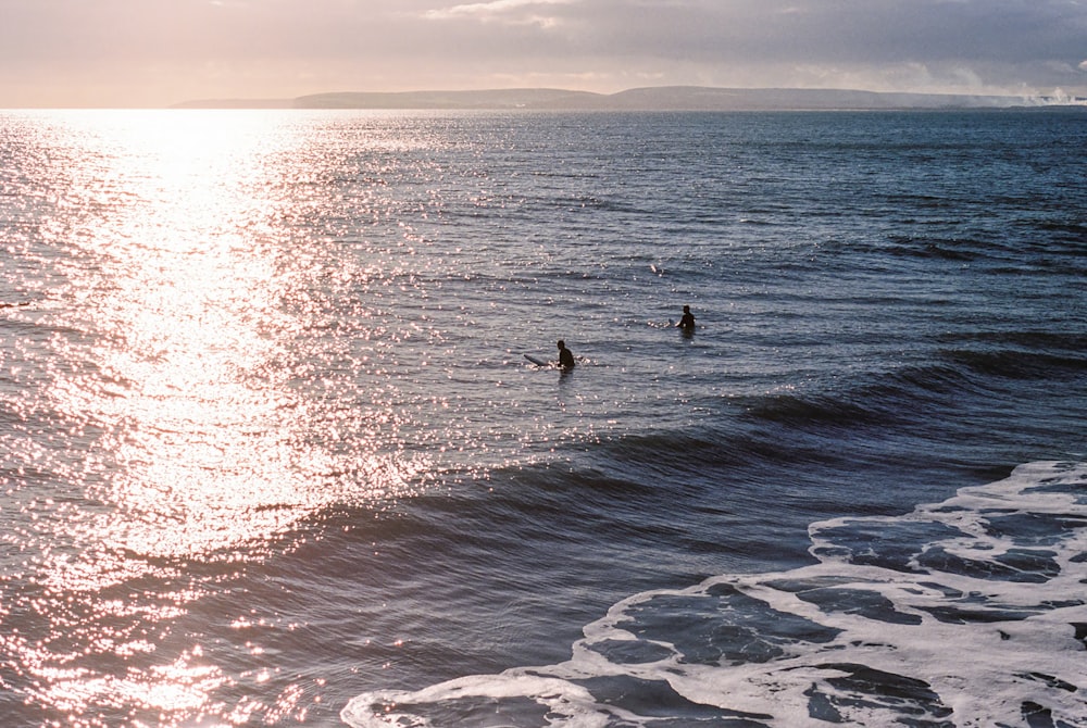 a couple of people riding waves on top of surfboards