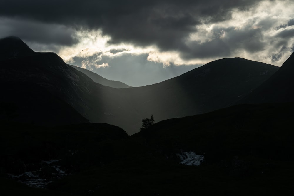 el sol brilla a través de las nubes en las montañas