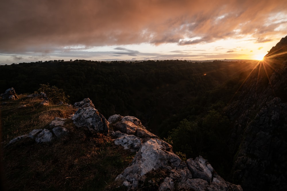 the sun is setting over a rocky cliff