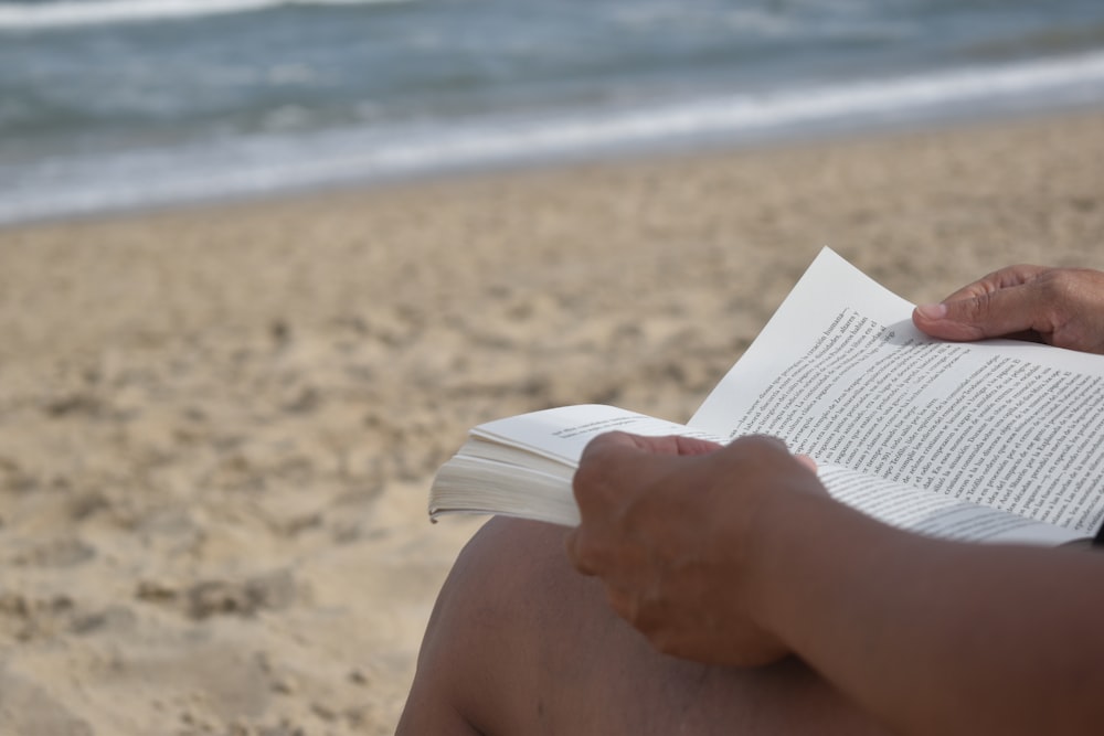 a person sitting on a beach reading a book