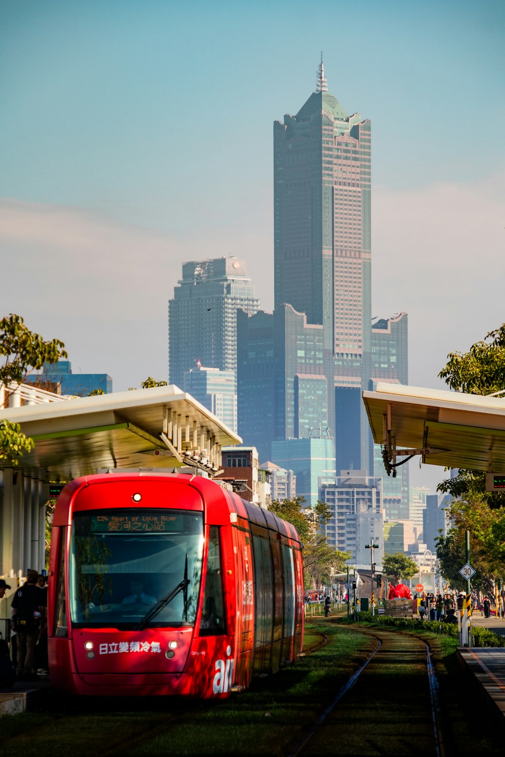 a red train traveling down train tracks next to tall buildings