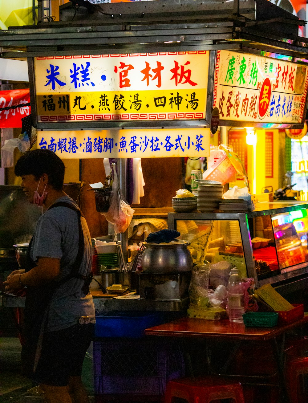 a man standing in front of a food stand at night