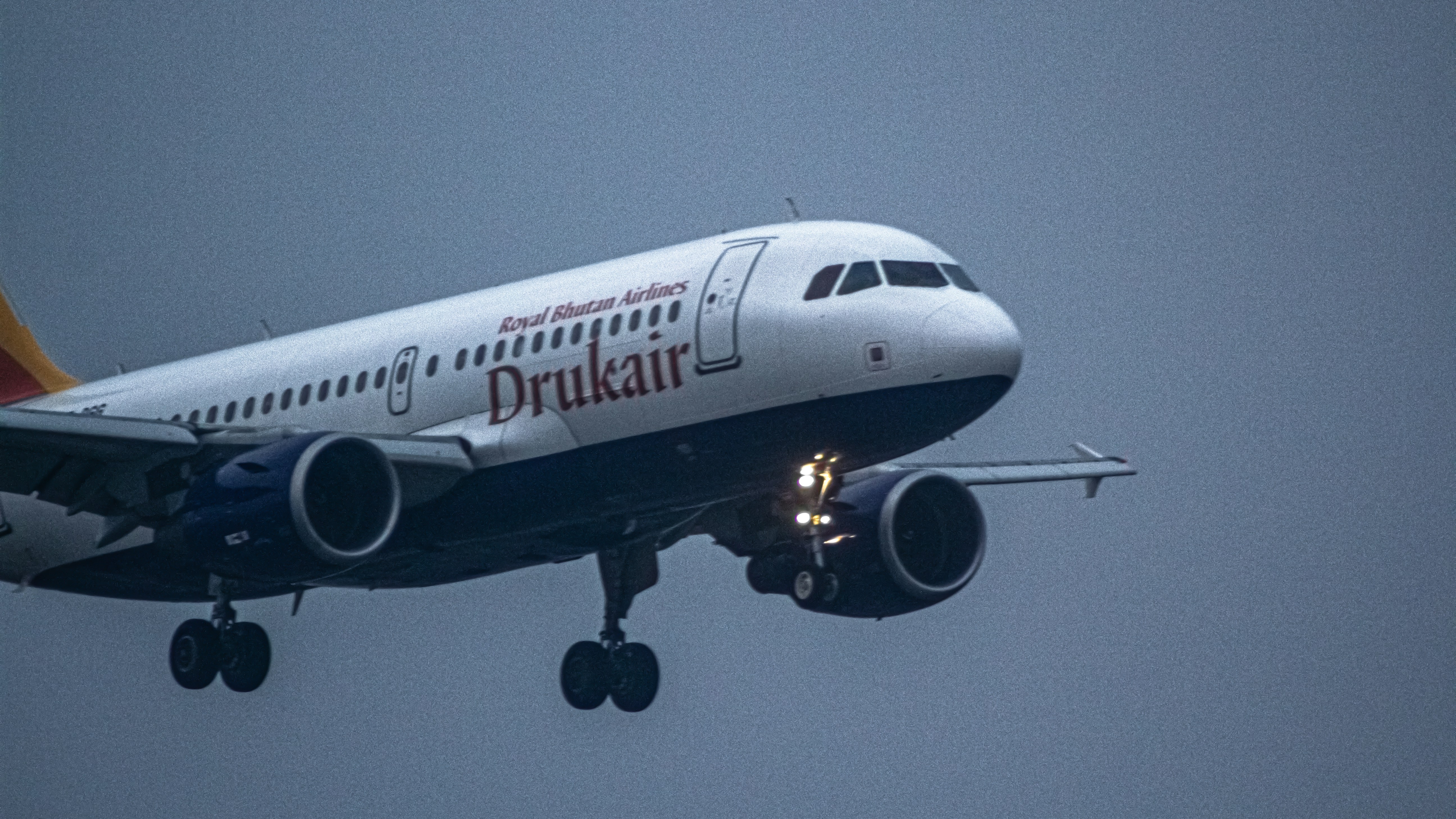 a large jetliner flying through a cloudy sky, Drukair a319 landing moment.