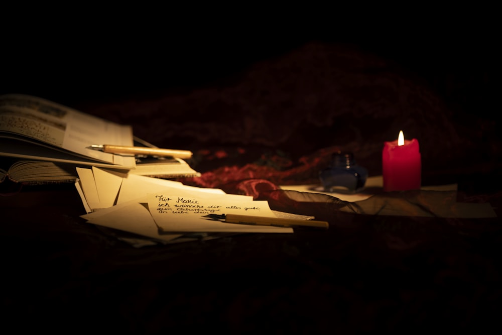 a pile of mail sitting next to a lit candle