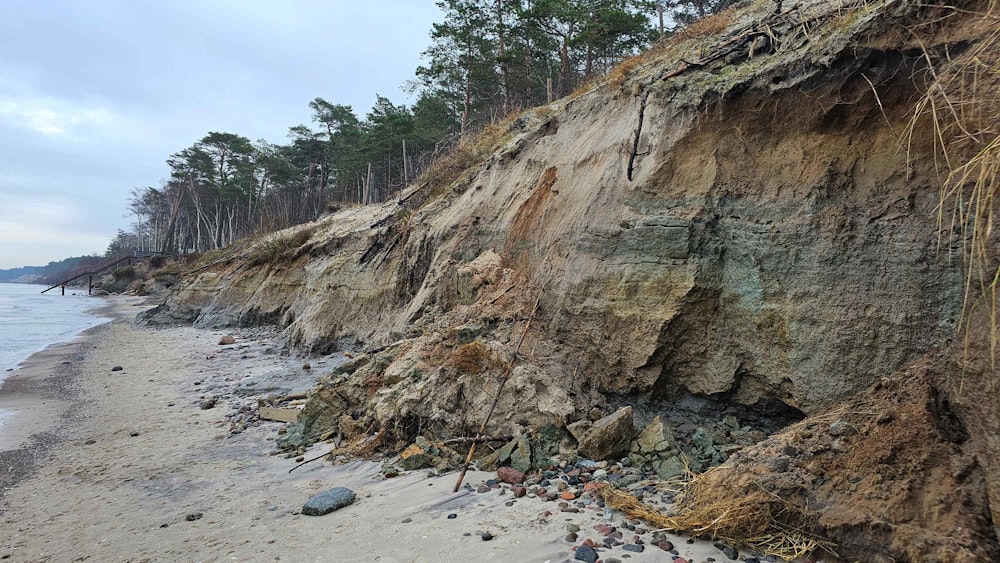 a rocky cliff on the shore of a beach